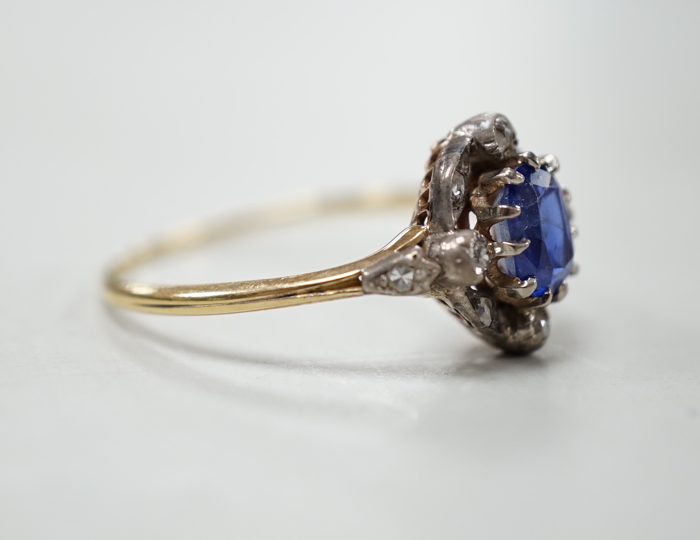 An early 20th century yellow metal, sapphire and diamond cluster set oval cluster ring, size R/S, gross weight 2.1 grams.